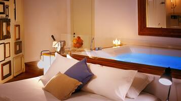 A hotel room with a bed, a bathroom with a bathtub, a mirror, and framed pictures on the wall.