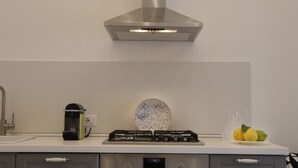 Una cocina moderna con extractor de acero inoxidable, horno empotrado y cocina a gas.