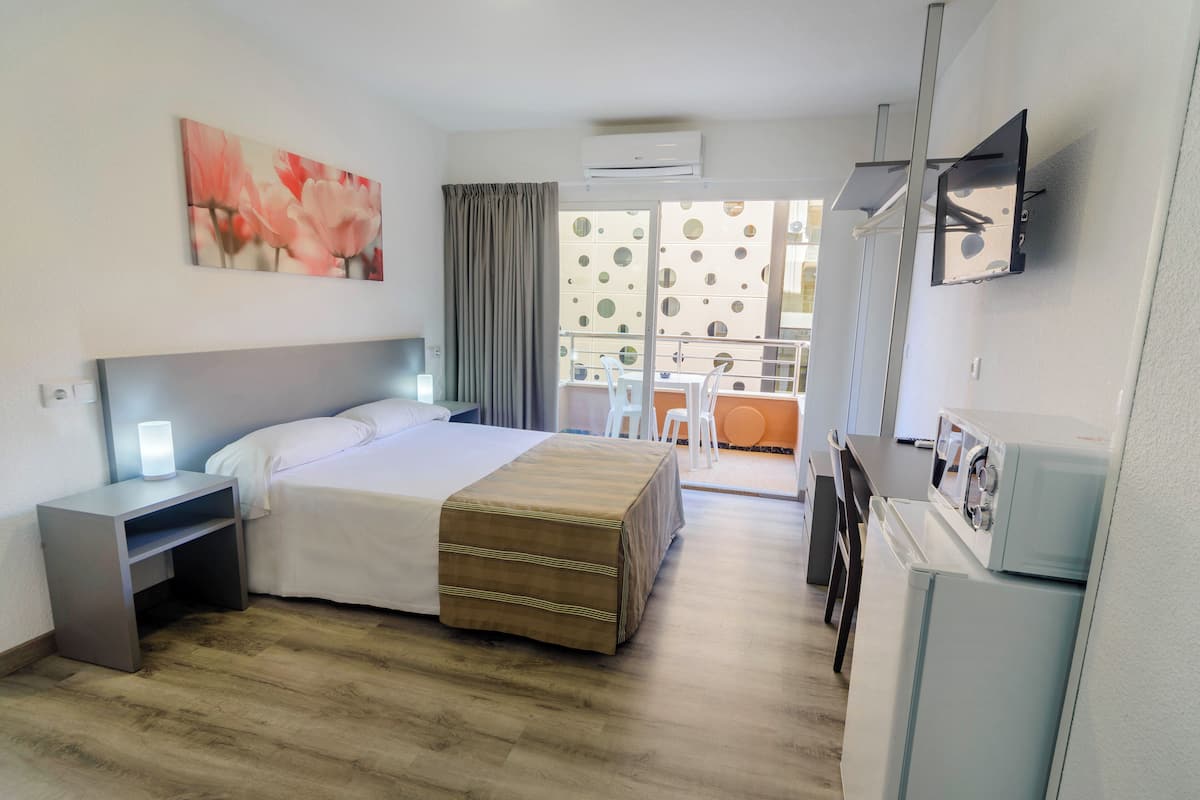 A hotel room with a bed, bedside table, lamp, and a view of the balcony.