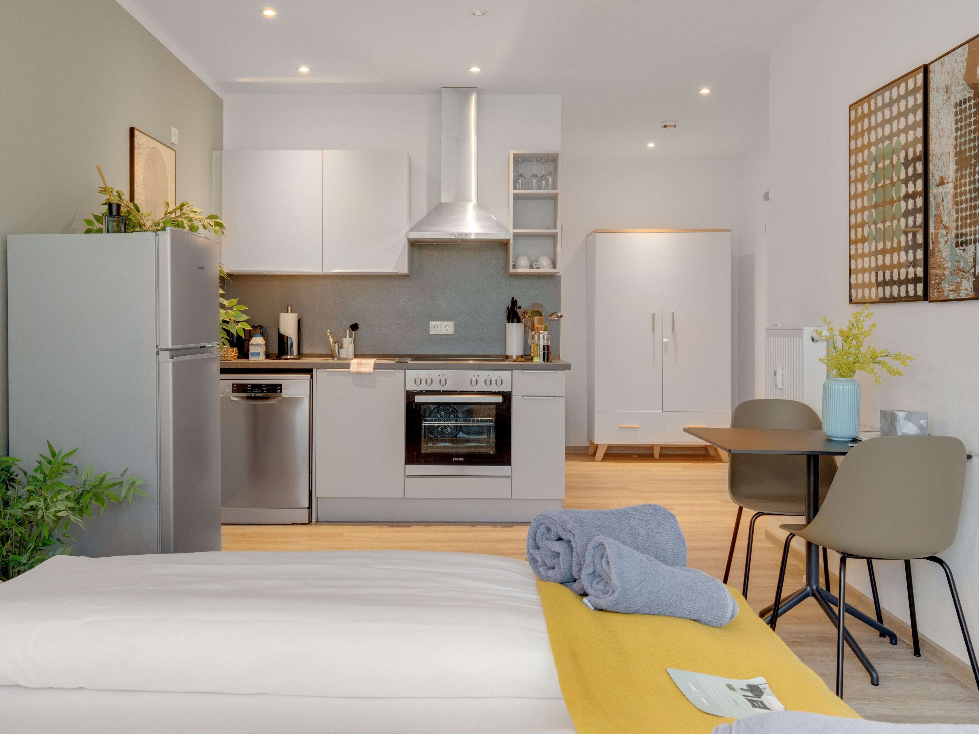 A modern kitchen with a stove, oven, and refrigerator. There is a dining area with a table and chairs.