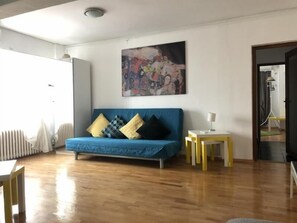 Una sala de estar con un sofá azul, un cuadro en la pared y un radiador.