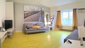 Ein modernes Wohnzimmer mit einer Couch, einem Fernseher und einem Gemälde einer Brücke.