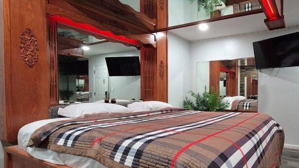 Un dormitorio con una cama grande, cabecera de madera y televisor montado en la pared.