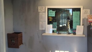Una habitación con ventana, una caja de madera con la etiqueta “FULL HOUSE” y varios avisos en la pared.