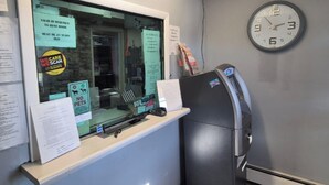 Una zona de recepción con un ventanal de vidrio, un reloj y un quiosco de autoservicio.
