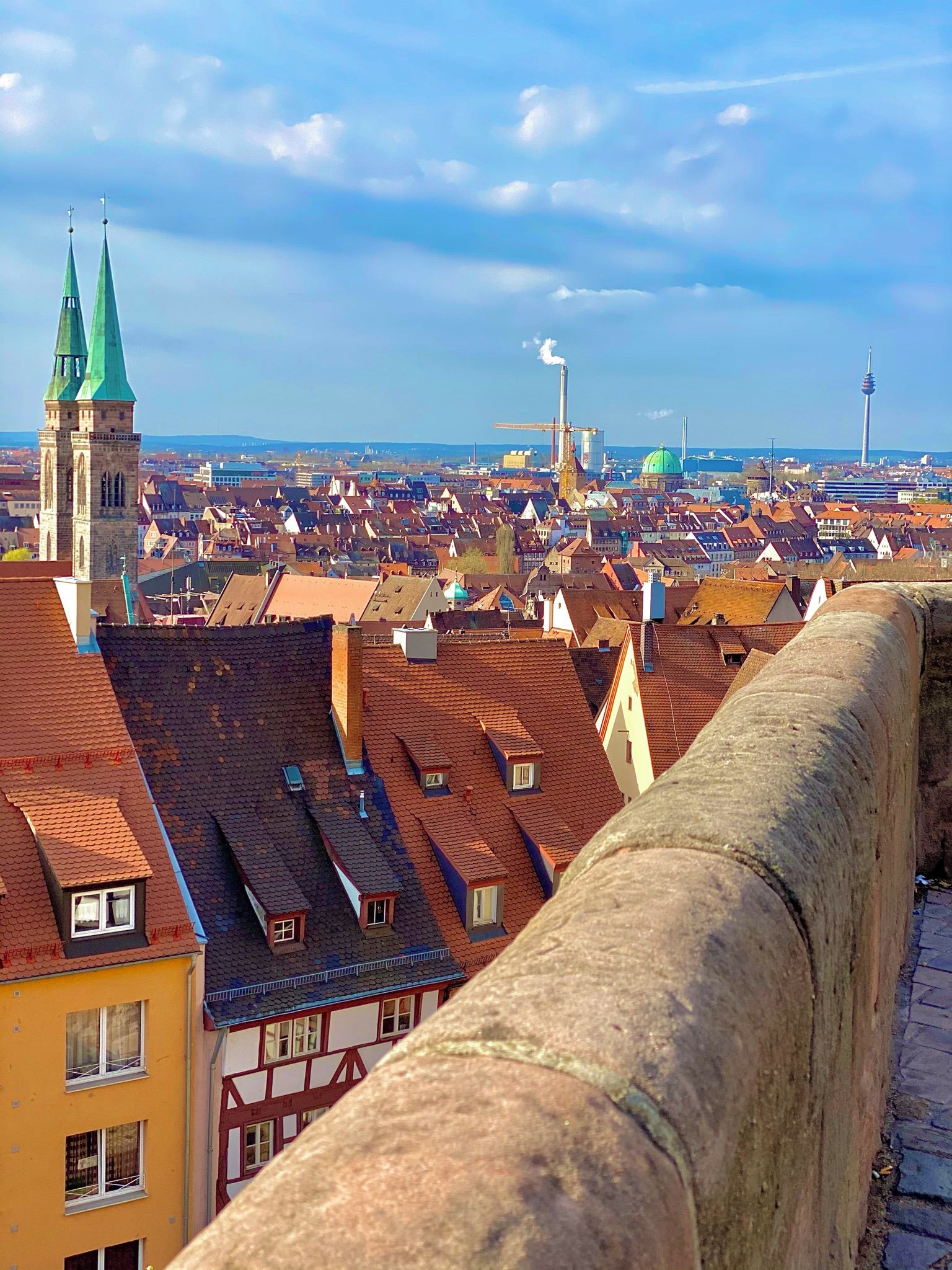 A cityscape with historic buildings, a prominent tower, and a modern tower in the distance.