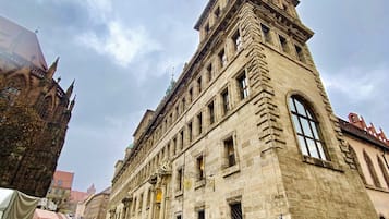 Un edificio histórico de piedra con un gran ventanal de arco y una torre en esquina.