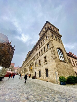 A historic stone building with a large arched window and a corner tower. - Burghotel Nürnberg (Nuremberg)