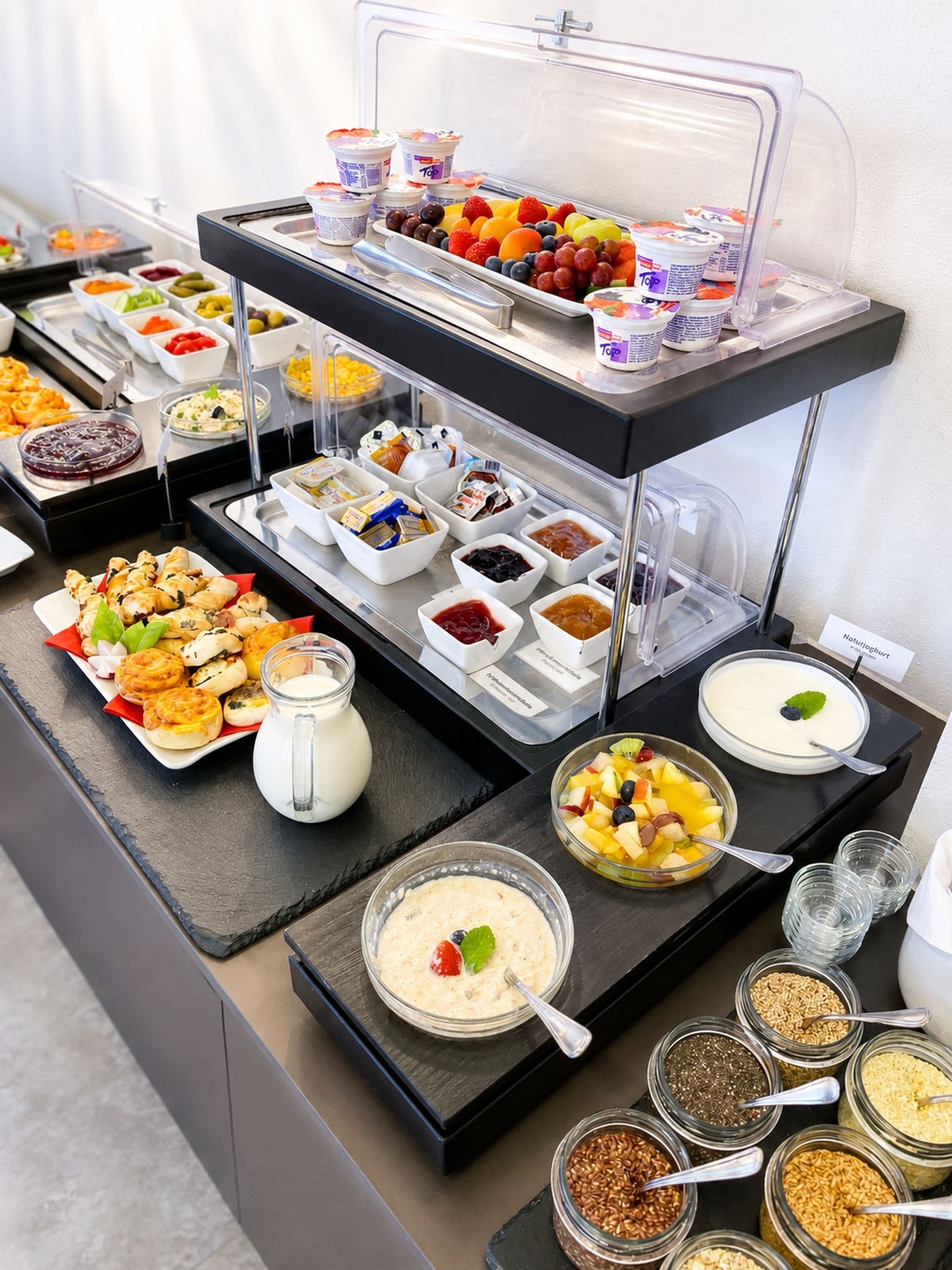 A buffet with various food items including fruits, yogurt, and cereal.