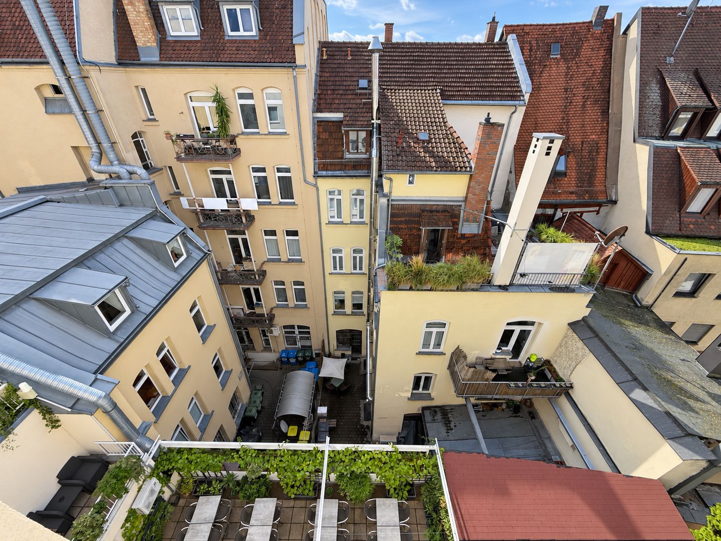 Ein mehrgeschossiges Wohngebäude mit Balkonen, einer Dachterrasse und einer sichtbaren Satellitenschüssel.