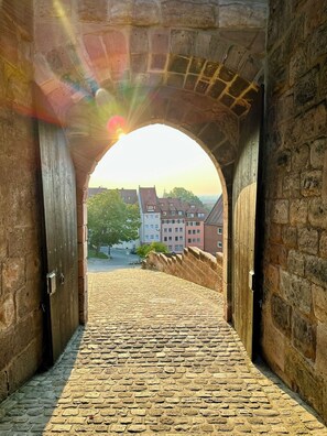 An arched stone bridge leading to a cobblestone path with buildings in the background. - Burghotel Nürnberg (Nuremberg)