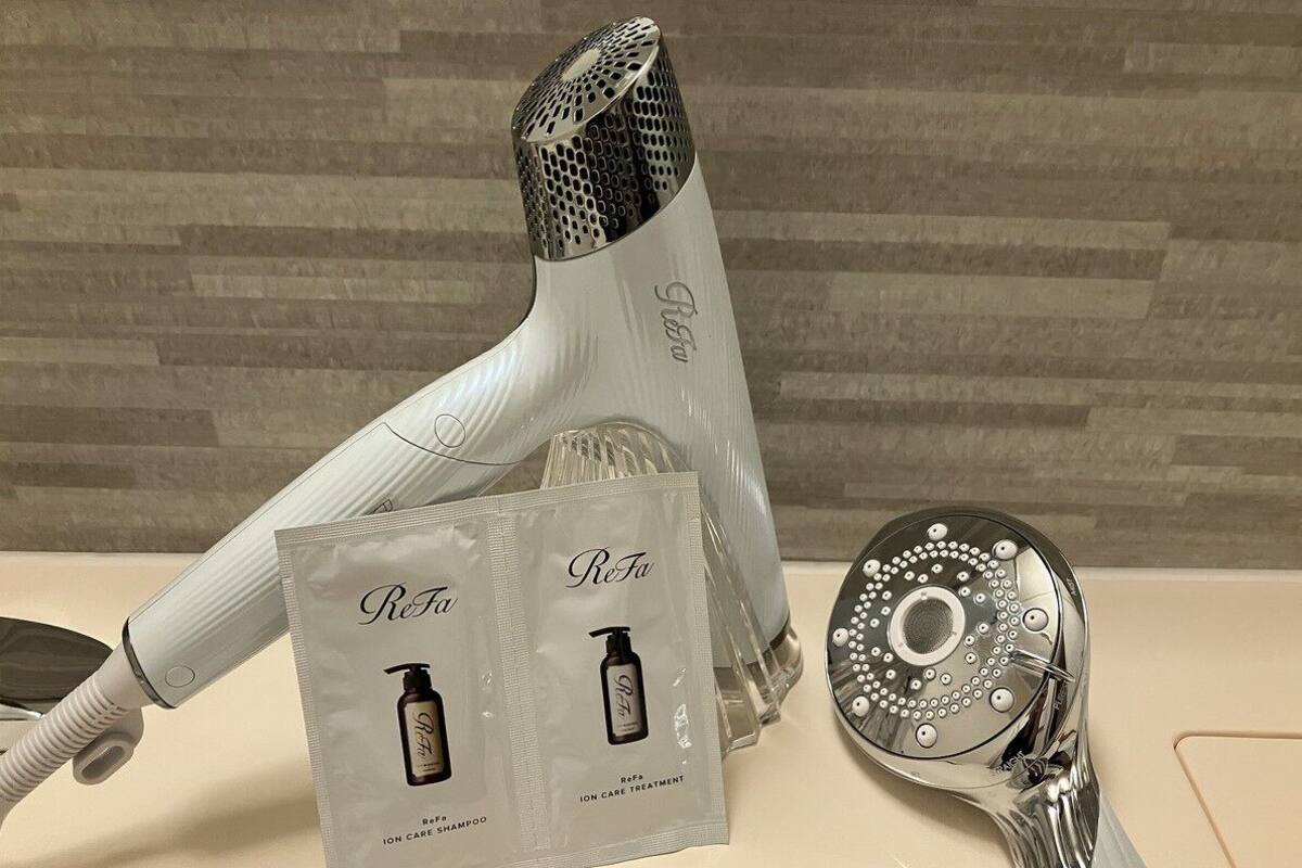 Une salle de bain équipée d’un robinet moderne, d’un sèche-cheveux et d’un ensemble de produits pour le soin des cheveux ReFa.