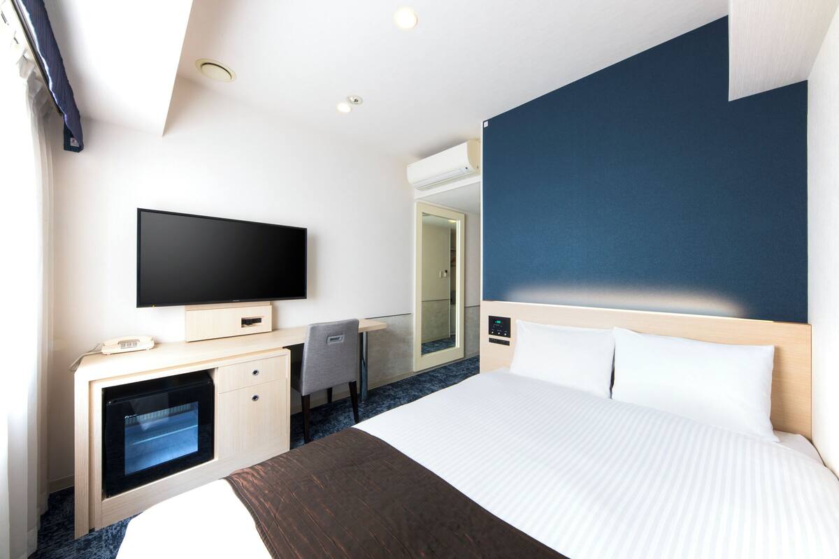 Une chambre d’hôtel équipée d’un lit, d’une télévision, d’un bureau et d’un mini-bar.