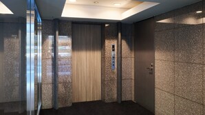 A modern elevator with a control panel, glass walls, and a carpeted floor. - Hotel Villa Fontaine Tokyo - Nihombashi Mitsukoshimae (Tokyo)
