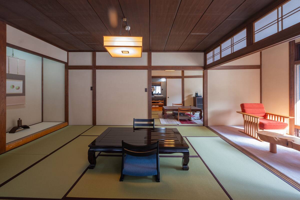 A traditional Japanese room with tatami flooring, a low table with a bench, and sliding doors.