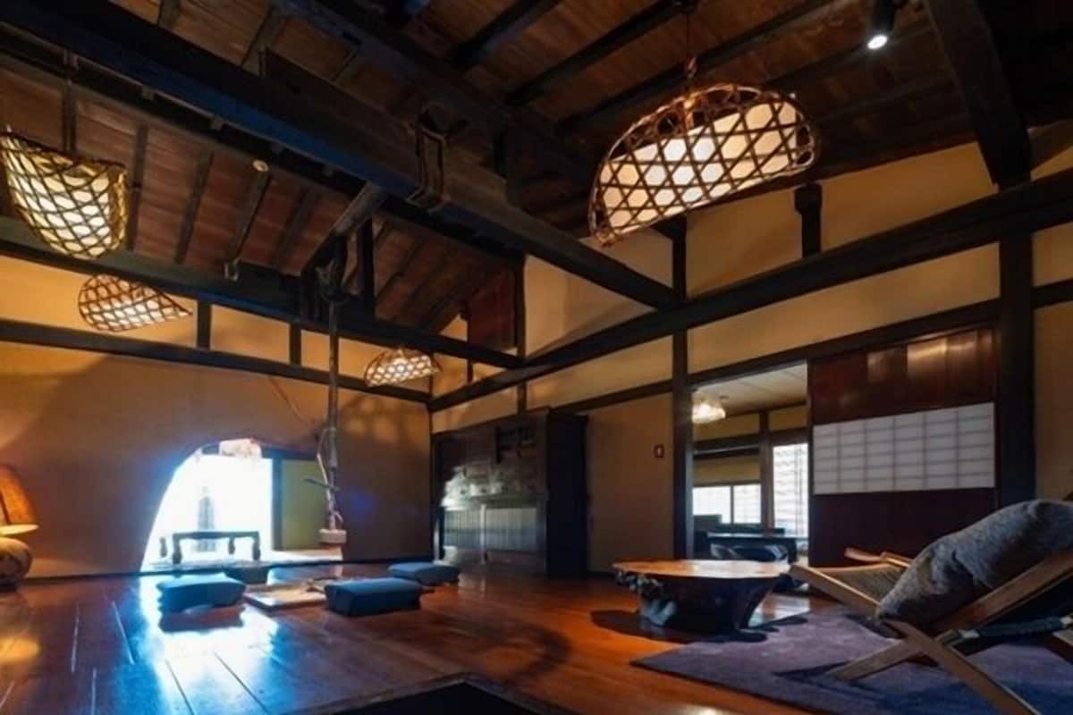 A traditional Japanese interior with tatami flooring, low wooden beams, and hanging paper lanterns.