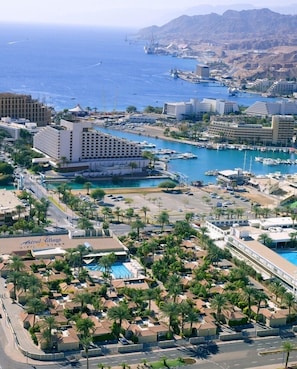 A coastal resort area with a marina, hotel buildings, and a residential neighborhood with palm trees. - Astral Village (Eilat)