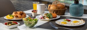 A breakfast setting with various dishes including eggs, toast, and a fruit salad. - Astral Village (Eilat)