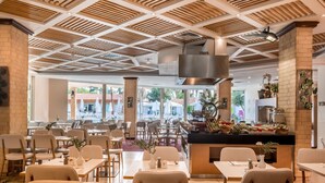 Un ristorante dall'ambiente moderno, con un bancone centrale ricco di cibi diversi, circondato da tavoli e sedie.
