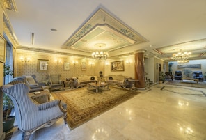 A spacious lobby with a large, ornate chandelier, plush seating, and a patterned carpet.