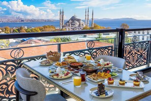 A balcony table with breakfast items and a view of a historic building with multiple minarets. - Rast Hotel Sultanahmet (Istanbul)