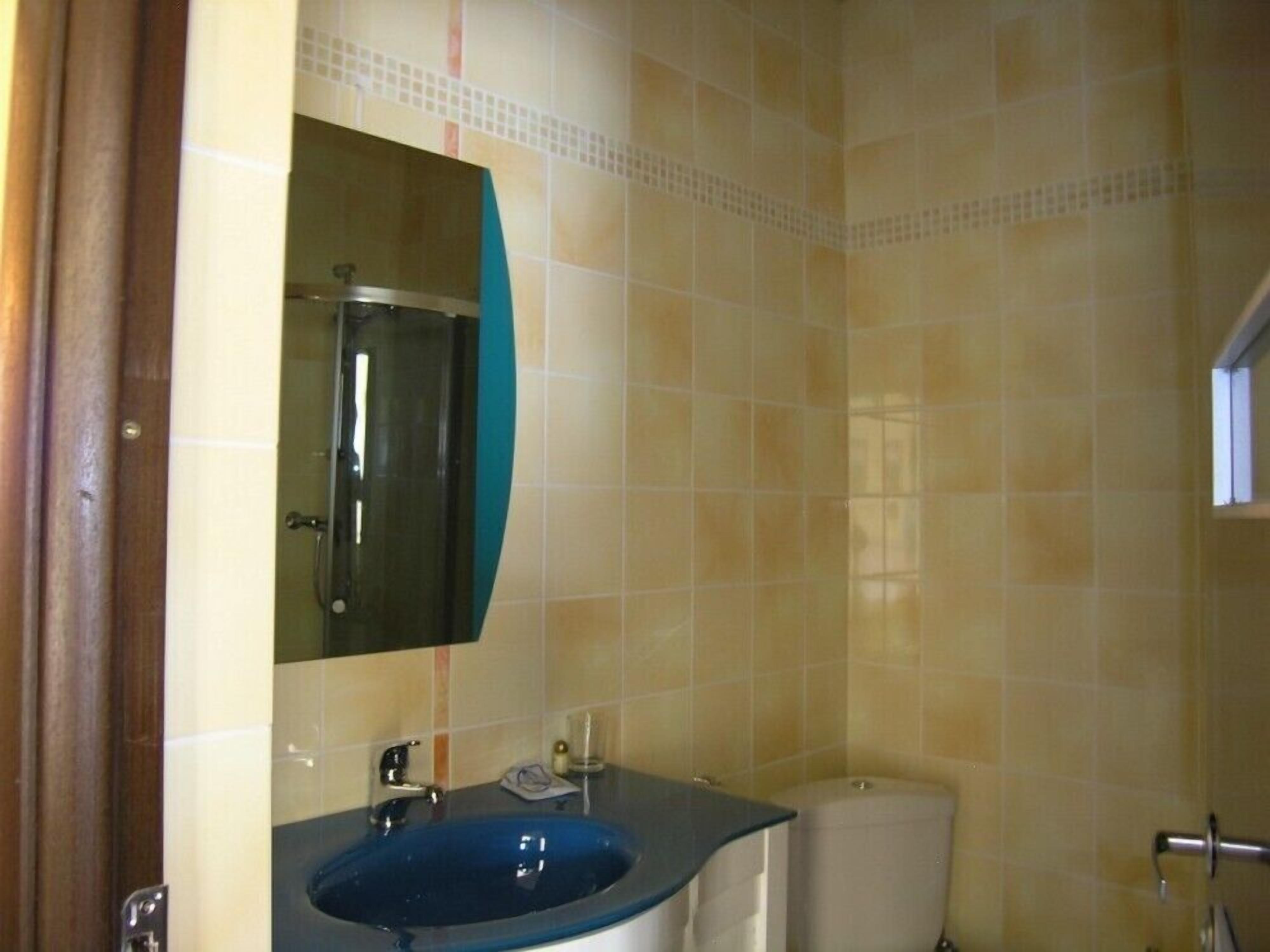 A bathroom with a blue sink, a mirror, and a toilet.
