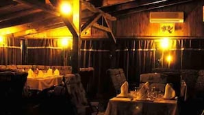 Un restaurant à la lumière tamisée, avec des murs et des tables en bois, préparé pour le service.