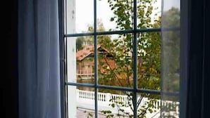 Une fenêtre donnant sur une maison et un arbre.