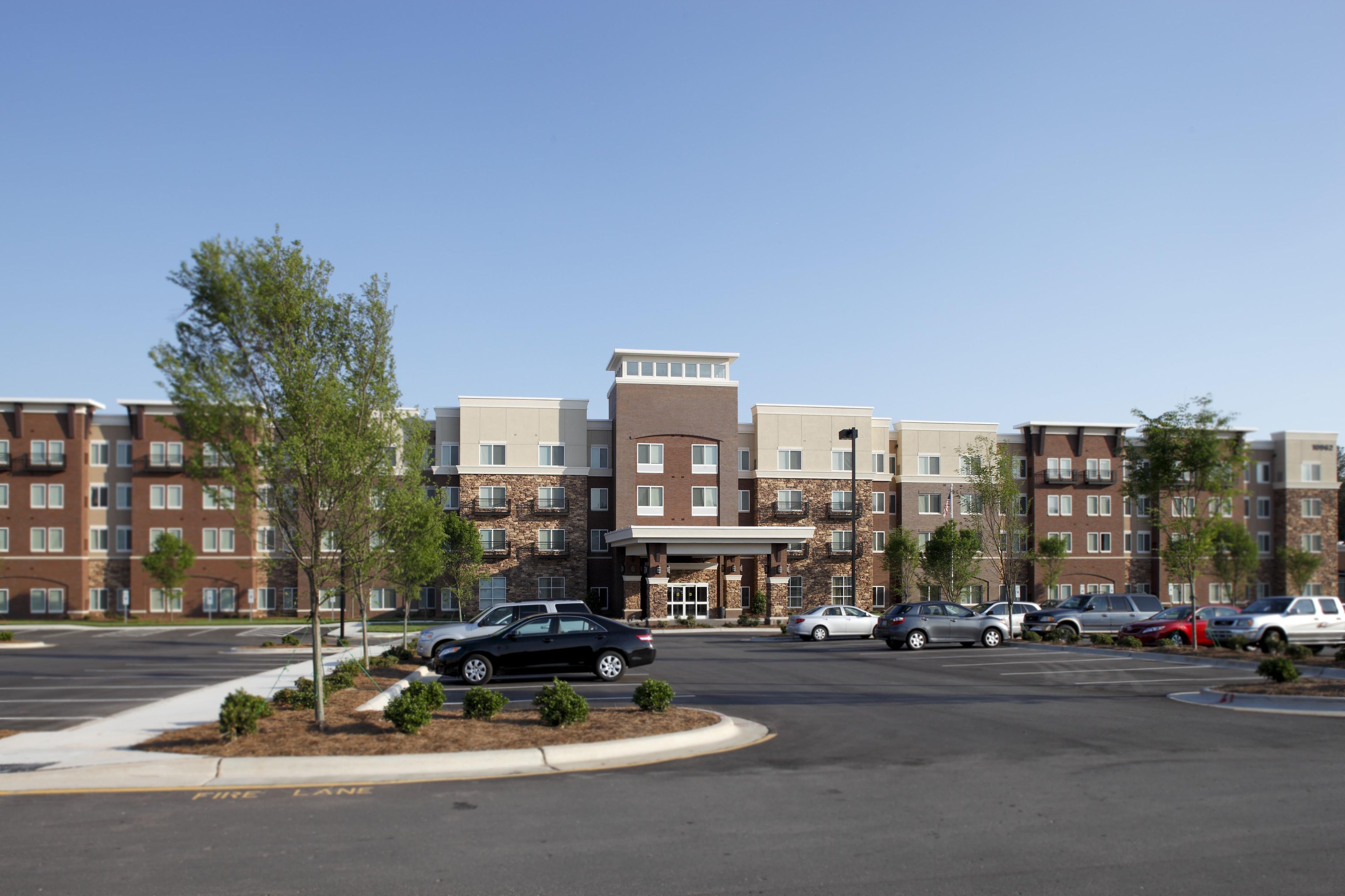 A multi-story hotel with a parking lot in front.