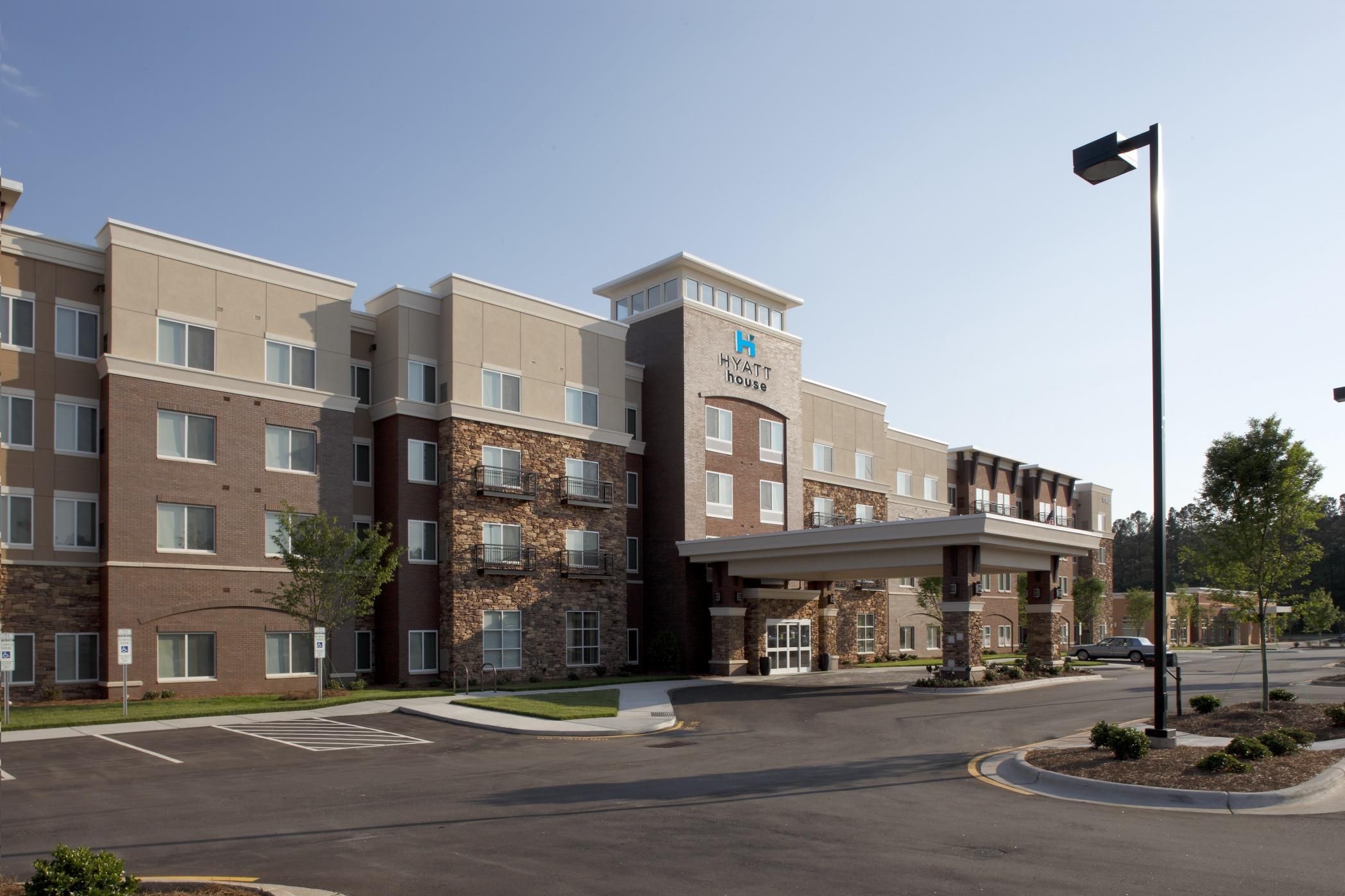 A multi-story hotel with a stone facade, a prominent 'Hyatt House' sign, and a covered entrance.