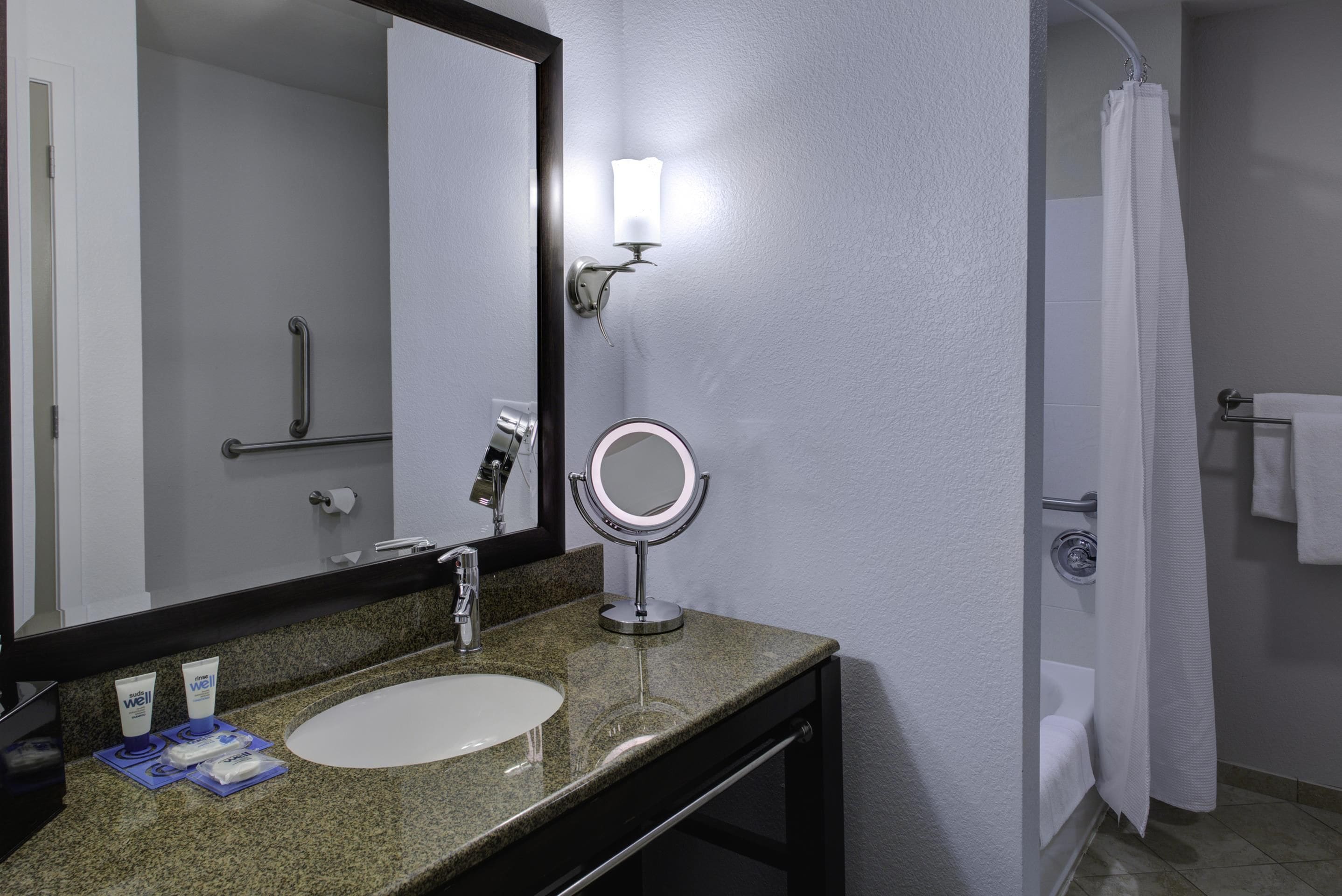 A bathroom with a sink, mirror, and a shower curtain.