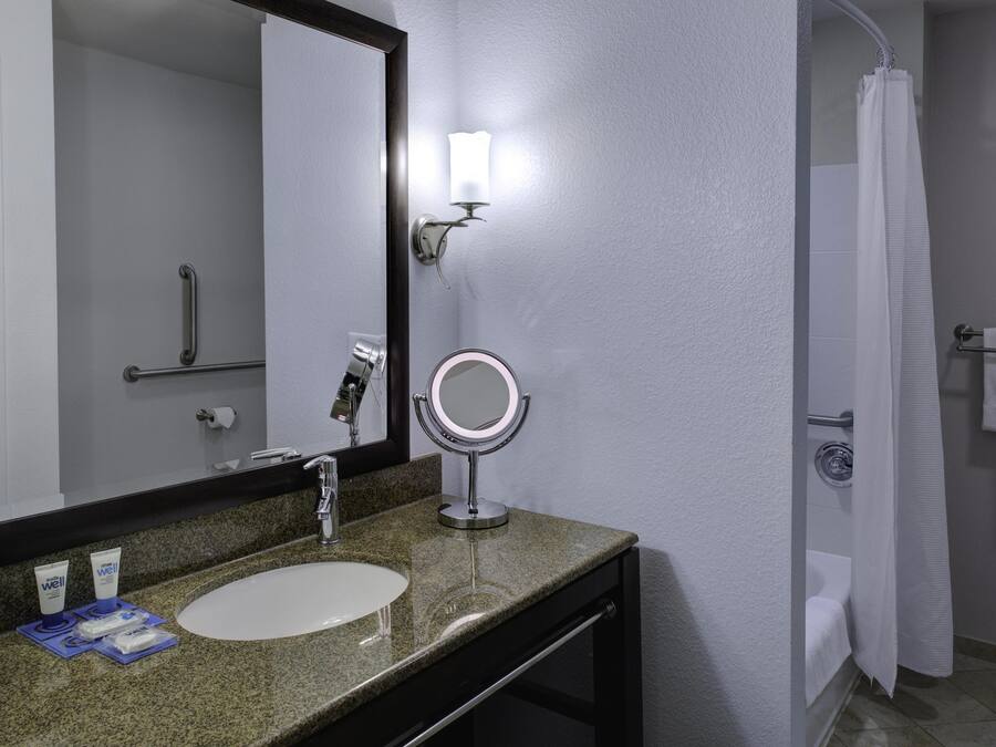 A bathroom with a sink, mirror, and a shower curtain.