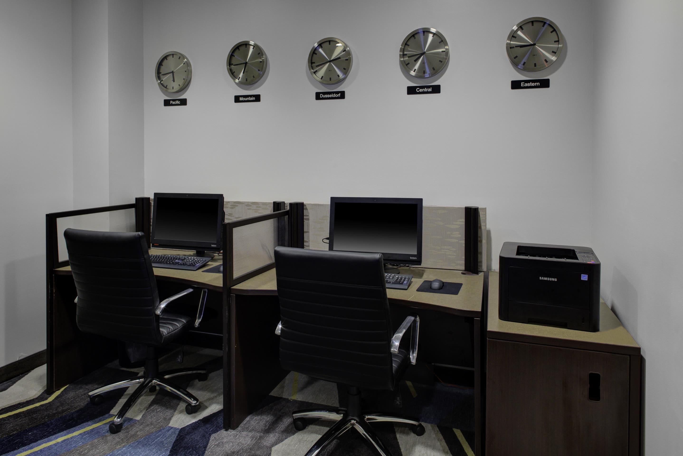 A workspace with four computer desks, each with a monitor and keyboard, and a printer on the right.