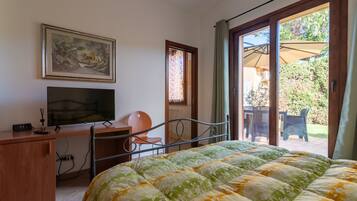 A bedroom with a bed, a desk, a chair, a television, and a window.