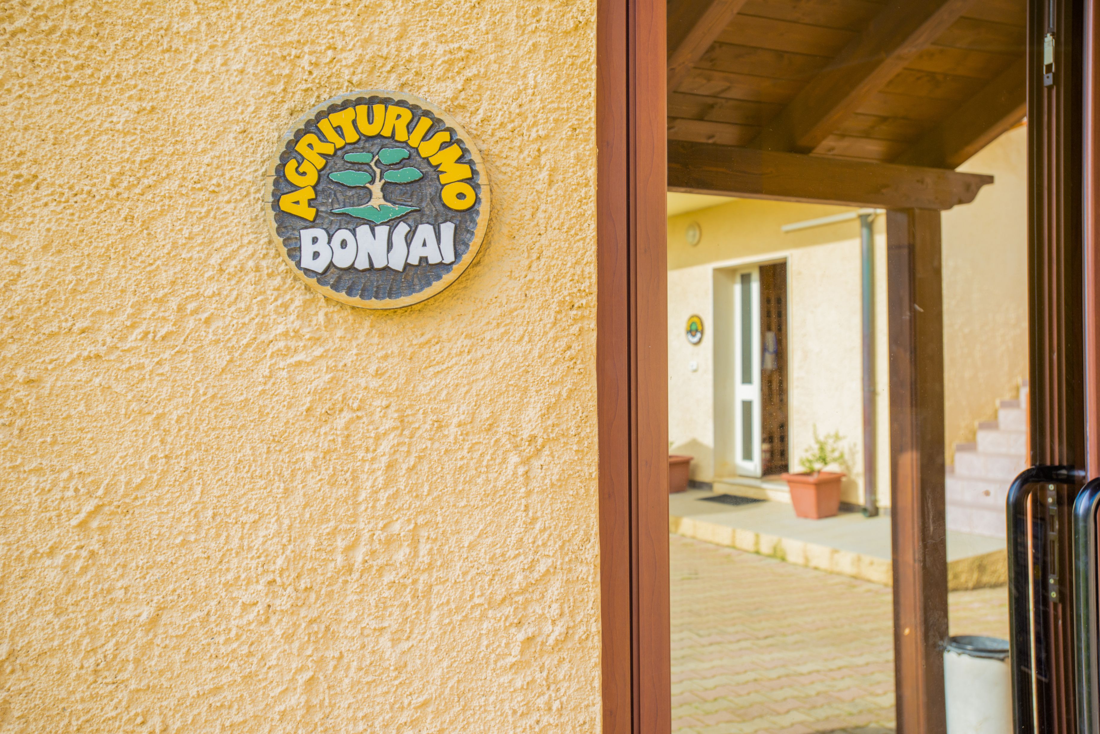 Un cartello con la scritta 'Agriturismo Bonai' su un muro dalla superficie irregolare.
