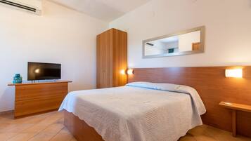 Ein Schlafzimmer mit Bett, Kommode, Fernseher, Kleiderschrank und Spiegel.