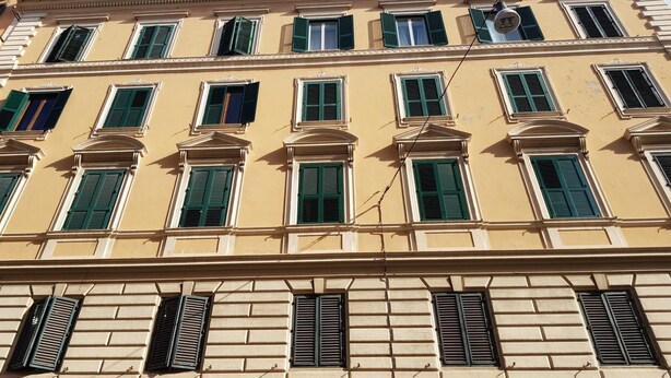 A multi-story building with a classical architectural style, featuring evenly spaced windows with green shutters and a symmetrical facade. - Pitagora (Rome)