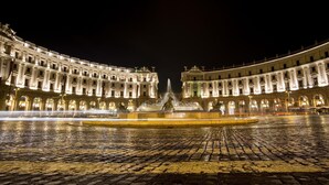 A historic building with a central fountain, arched windows, and a cobblestone plaza. - Pitagora (Rome)