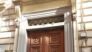 A double wooden door with a decorative design, set in a building with stone walls and a classical architectural style. - Pitagora (Rome)