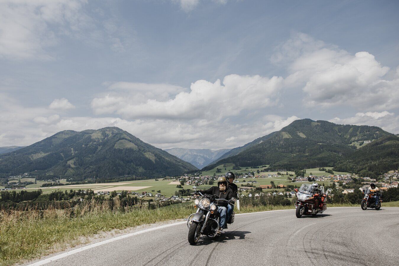 A group of motorcyclists on a road with a mountainous landscape in the background.
