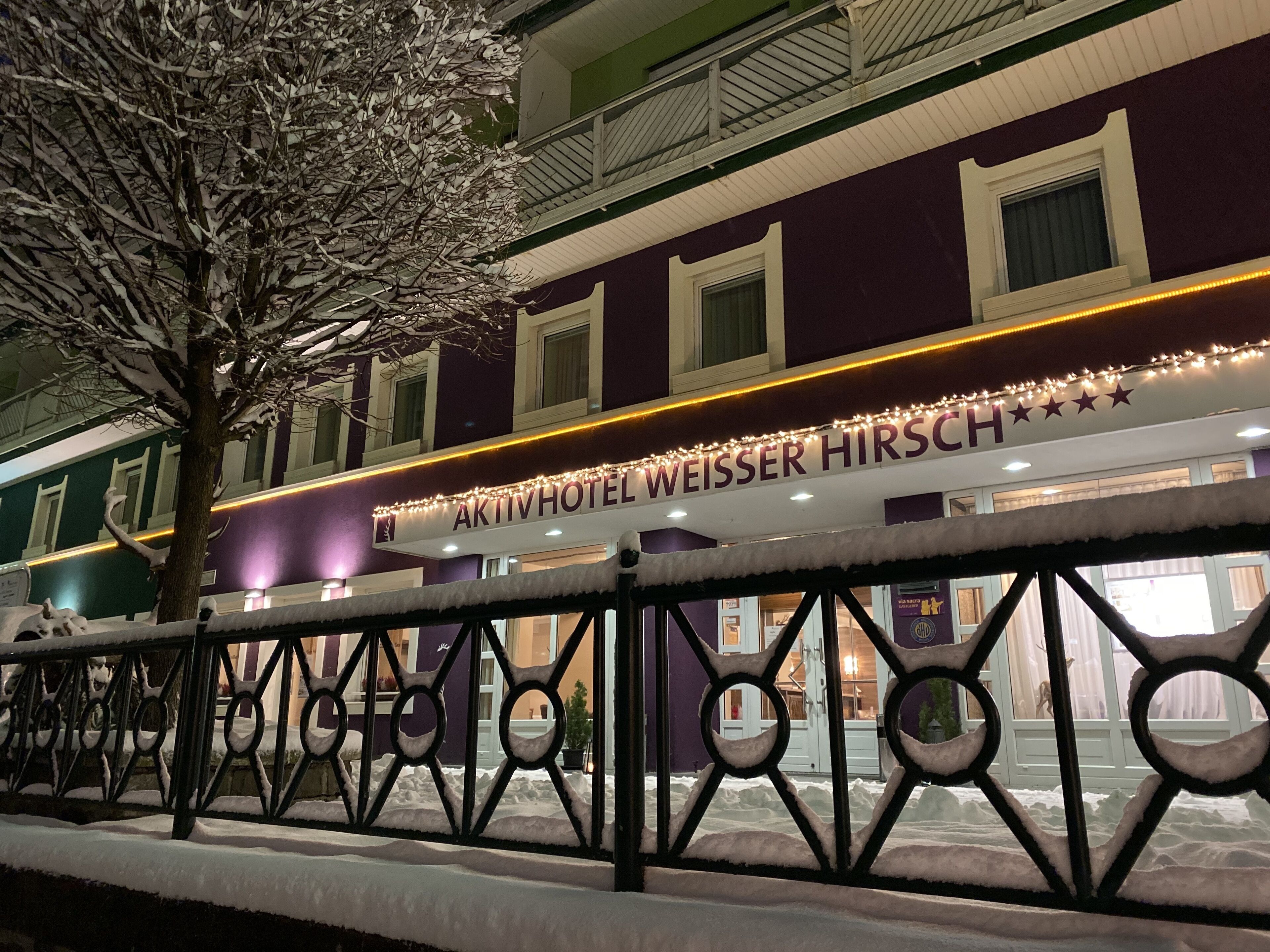 A hotel with a sign reading "Weisser Hirsch" and a snow-covered exterior.