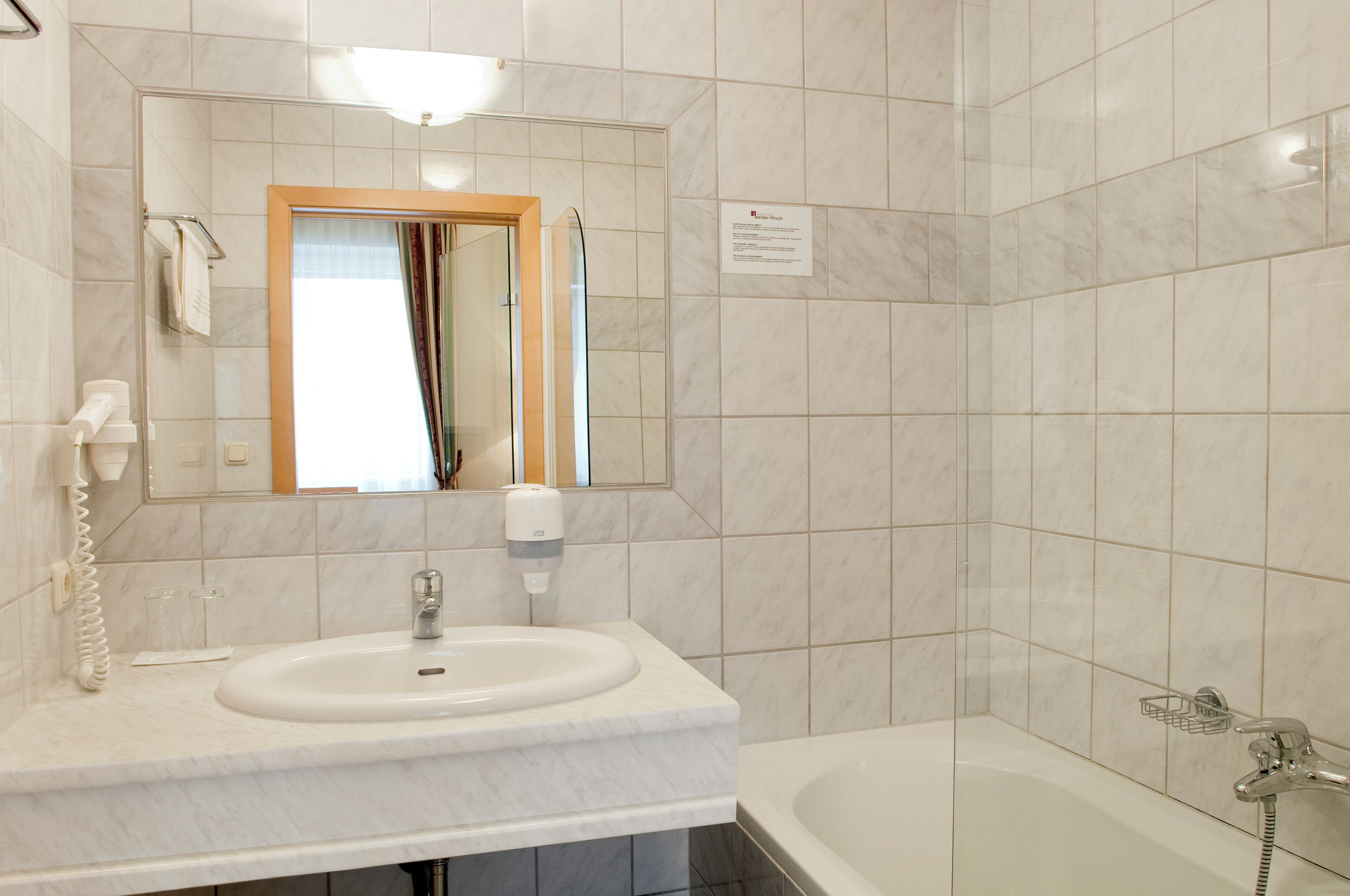Un baño con lavamanos, espejo y bañera.