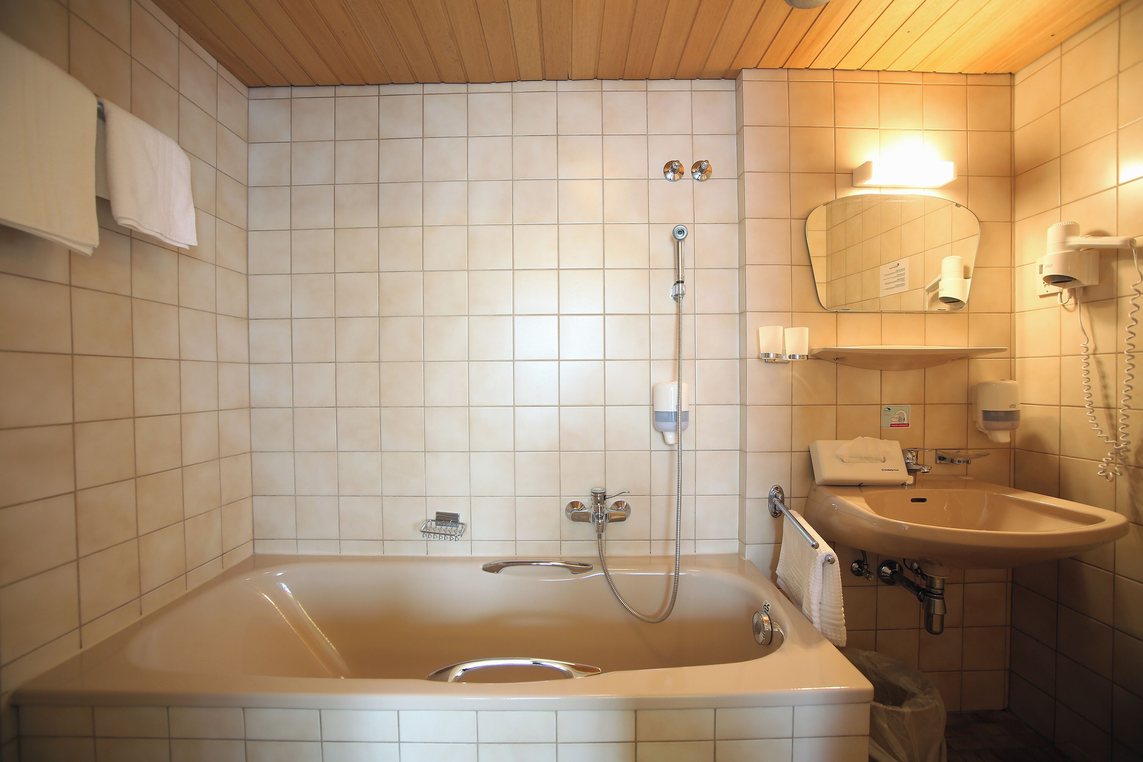 A bathroom with a bathtub, a sink, a mirror, and a towel rack.