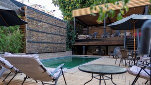 A poolside area with lounge chairs, a table, and umbrellas. - Happy House Hostel (Santiago)