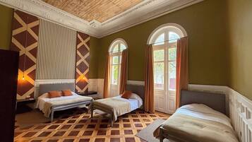 Habitación con dos camas, piso de parqué de madera y techo decorativo.