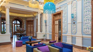 A spacious lobby with multiple seating areas, including sofas and armchairs, and a large wooden door. - Happy House Hostel (Santiago)