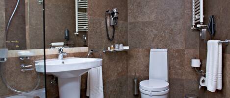 Un baño moderno con lavamanos, inodoro, ducha y zona de ducha con mampara de vidrio.