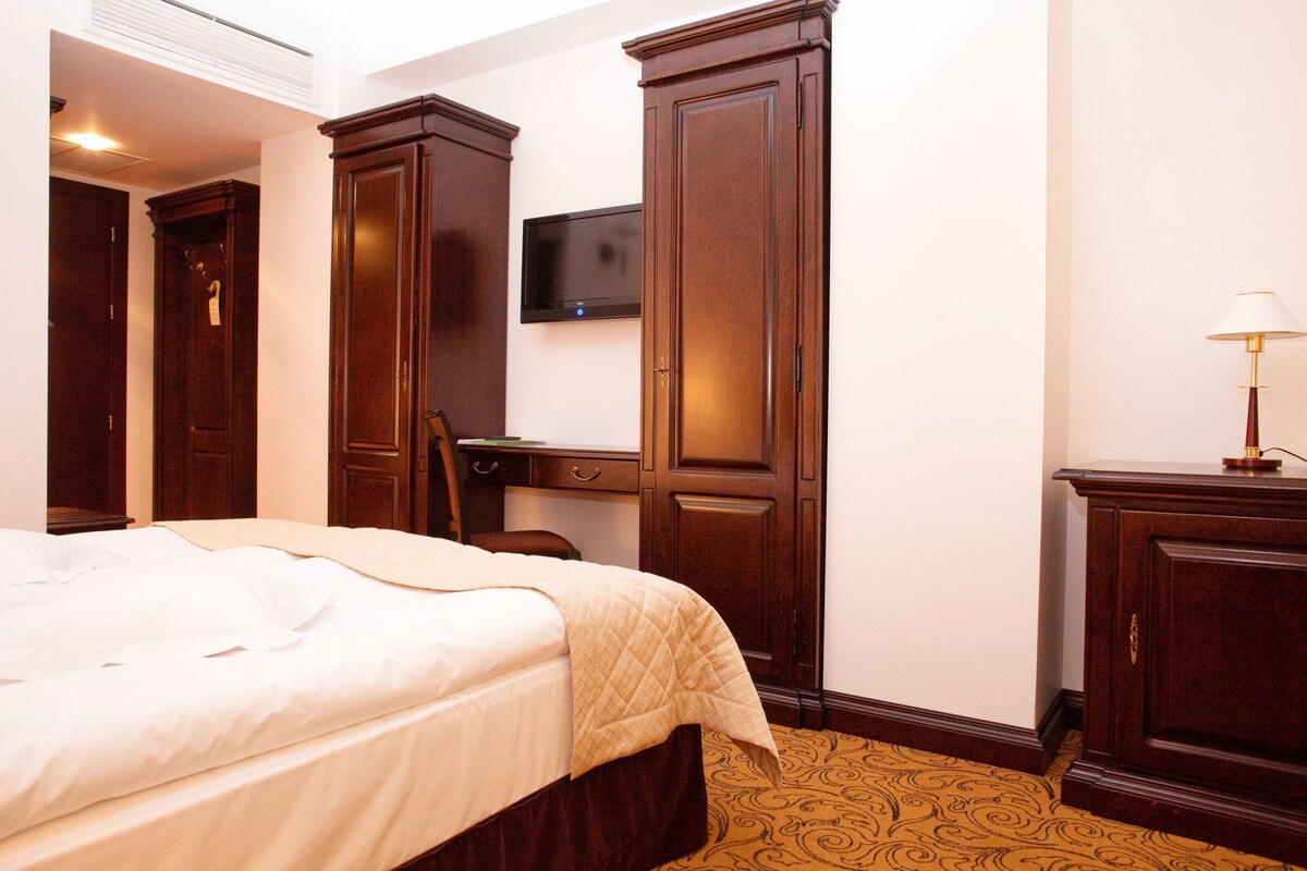 Una habitación de hotel con cama, escritorio, televisión y lámpara.