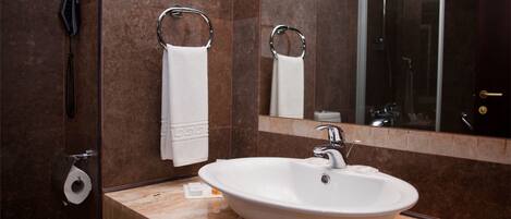 Une salle de bain avec un lavabo blanc, un miroir et un porte-serviettes.