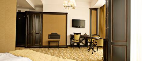 A hotel room with a bed, a desk with a chair, a television, and a large wardrobe.